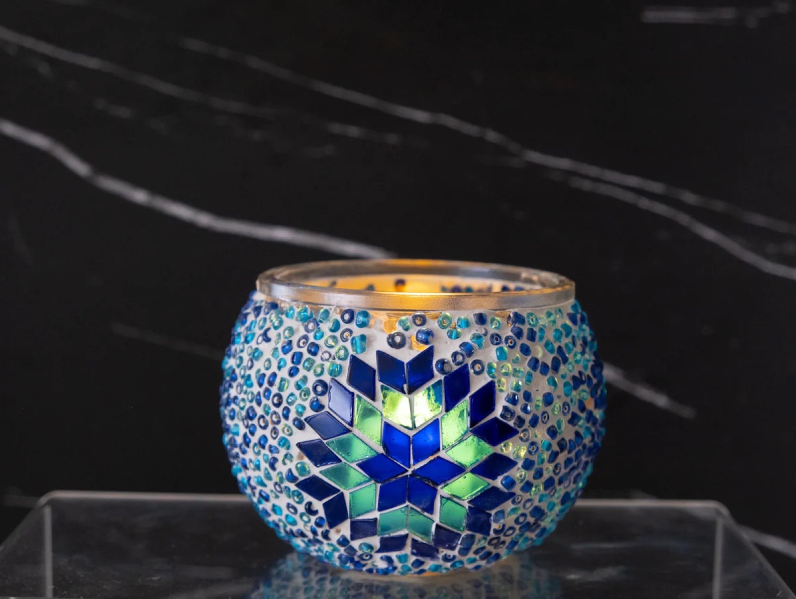 A candle in a blue mosaic holder