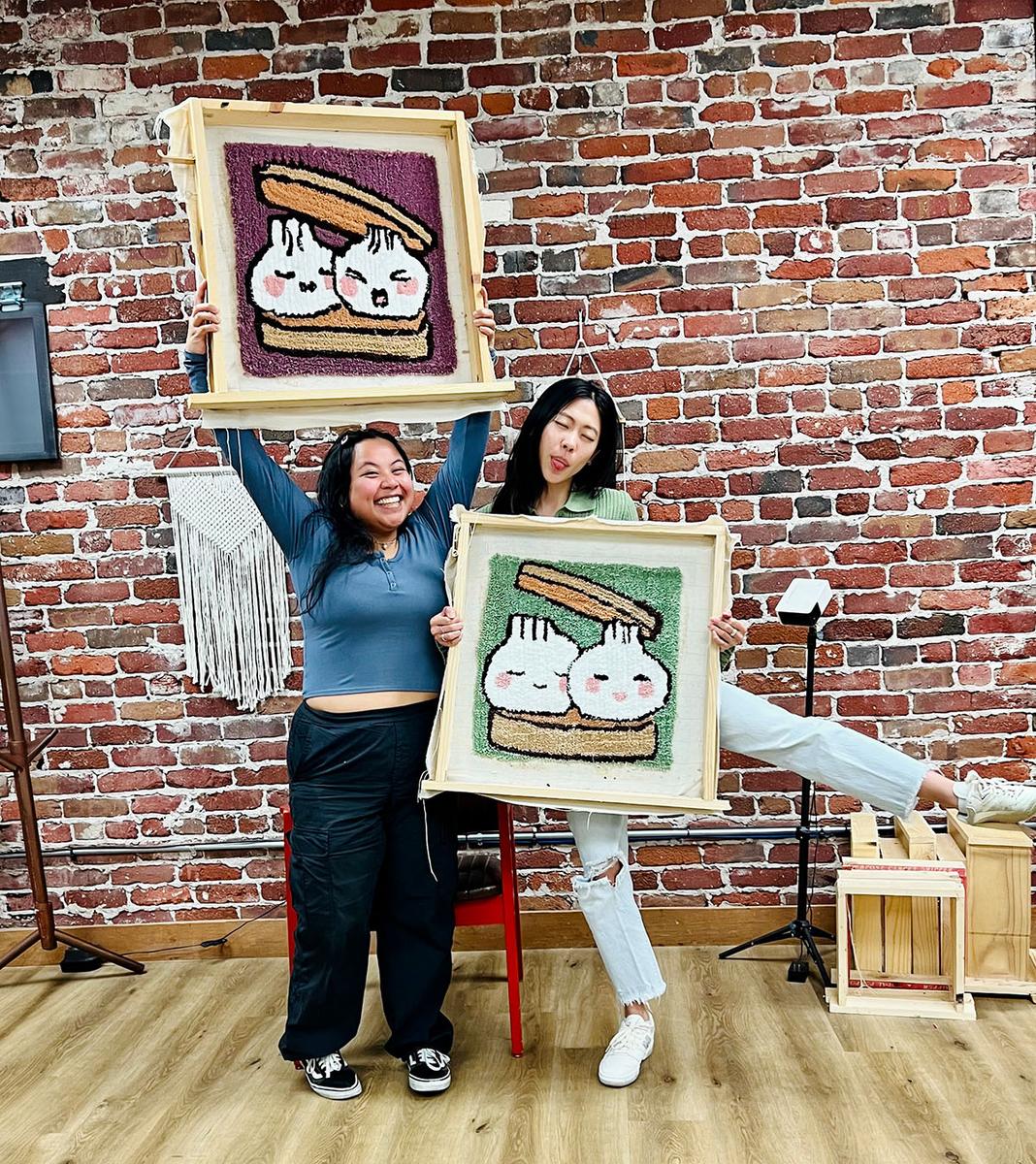 Two people holding the rugs they made